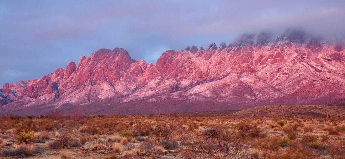 The Organ Mountains glowing pink at sunset above the desert east of Las Cruces, New Mexico